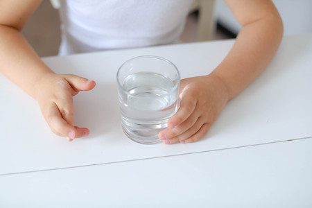 Cute smiling boy with glass of water isolated on a white background.の写真素材
