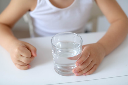 Cute smiling boy with glass of water isolated on a white background.の写真素材
