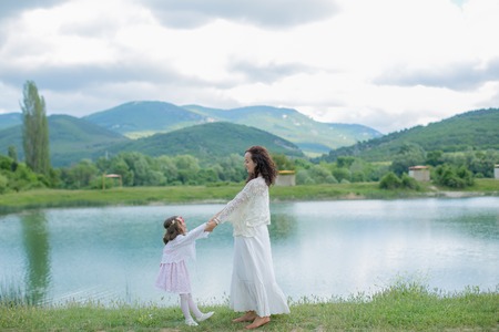 Mother and daughter in a meadow near a mountain lake.の写真素材