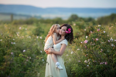 Happy family: a young beautiful pregnant woman with her little cute daughter walking in the wheat orange field on a sunny summer day. Parents and kids relationship. Nature in the countryの写真素材