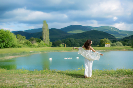 Beautiful bride in gorgeous white wedding dress standing near the lake Morskie Oko in the mountains on sunny summer day.の写真素材