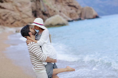 Vacation couple walking on beach together in love holding around each other. Happy interracial young couple, Woman and Caucasian man.の写真素材