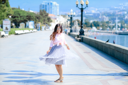 Girl walking along the seafront in dress in hot summer day.の写真素材