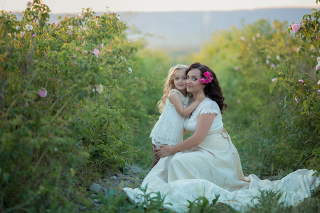 Happy family: a young beautiful pregnant woman with her little cute daughter walking in the wheat orange field on a sunny summer day. Parents and kids relationship. Nature in the countryの写真素材