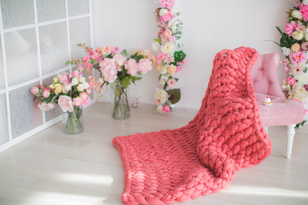 Soft fluffy plaid in the interior with flowers chair and cup of coffee.の写真素材