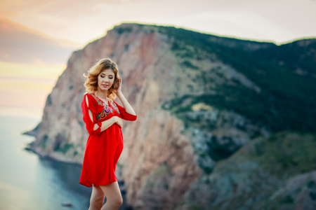 female travel nature scenery landscape concept of lady in red dress stay on edge of mountain top above south sea in summer bright weather with little wind on cape.の写真素材