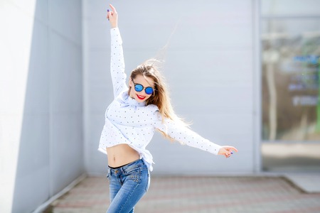Shapely young woman with long hair dancing outdoor relaxing with smile and eyes closed. Portrait of chilling blonde girl.の写真素材