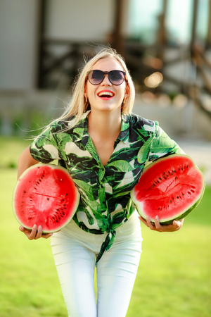 Beautiful smiling young woman holding sweet juicy watermelon in hands.の写真素材