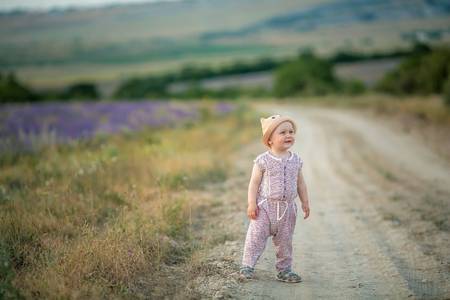 Outdoor portrait of a cute little child, a baby or toddler girl with her dog, a yellow labrador sitting on the groundの写真素材