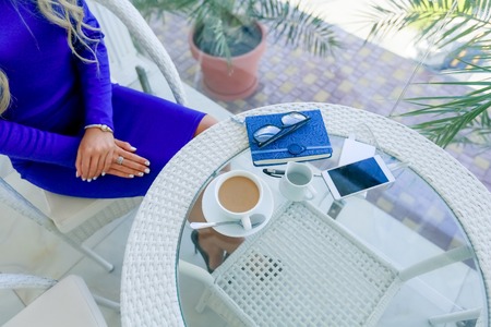 The girls hands on a table near a cup of coffee and a Notepad. White mobile phone for business.