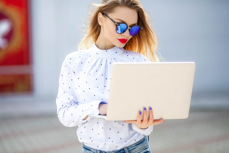 Closeup portrait of smiling blonde girl in eyeglasses holding notebooks.の写真素材