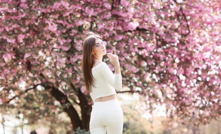 Alone beautiful girl with a romantic hairstyle and a professional make-up enjoys a smell of pink...
