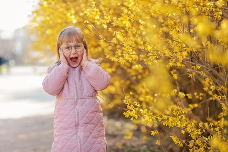 Stylish child girl 5-6 year old wearing trendy pink coat in autumn park. Looking at camera. Autumn season. Childhood. Shes posing as a modelの写真素材
