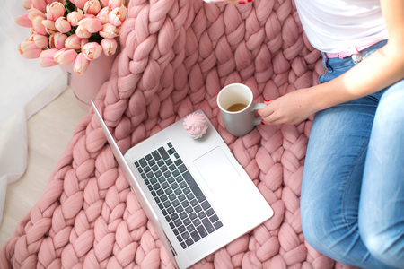 Cozy morning, a fluffy plaid, a laptop, and beautiful female feet.
