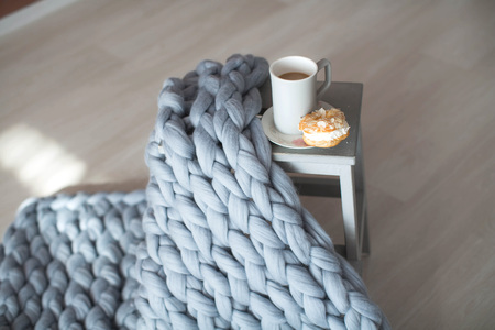 Soft fluffy plaid in the interior with flowers chair and cup of coffee.の写真素材