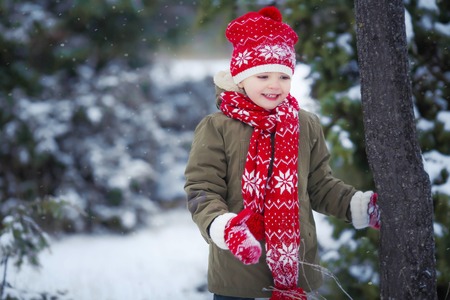 Funny little kid boy in colorful clothes playing outdoors during snowfall. Active leisure with children in winter on cold snowy days. Happy child having fun and playing with snow.の写真素材