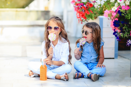 A Two cute little sisters eating huge lollipops outdoors on beautiful summer dayの写真素材