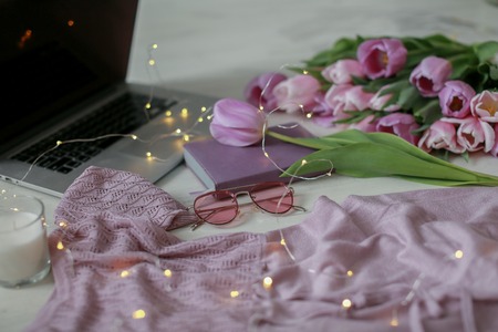 Laptop on wooden floor with coffee tulips and notepad.の写真素材