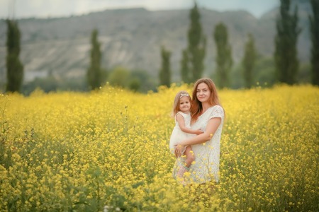 Happy mother and daughter child together with yellow dandelion flowers in summer day.の写真素材