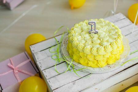 Yellow color concept of festive decorations with cake and candles 1 year.の写真素材