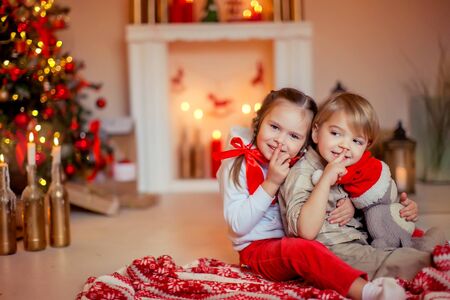 Children on Christmas eve a boy and a girl have fun and have fun on the floor near the Christmas tree.の写真素材