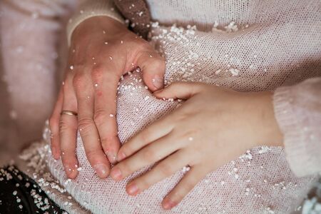 Hands of a pregnant woman and a man on a womans stomach.の写真素材