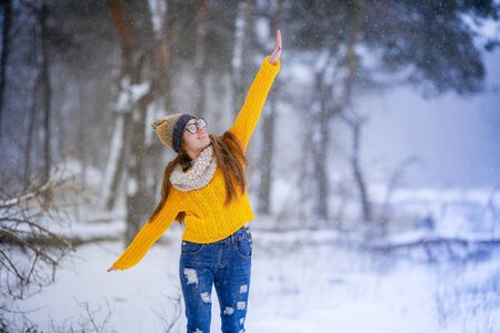 Cheerful woman in a scarf and warm clothes on the background of the winter forest.の写真素材