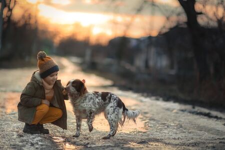 A boy with a dog on the street near a puddle during sunset.の写真素材