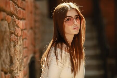 stylish woman in glasses young model in an urban area of the city near the brick walls.