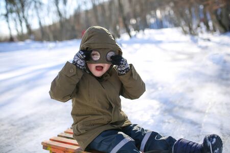 Boy sledding on the street in the snowy winter in the mountains.の写真素材