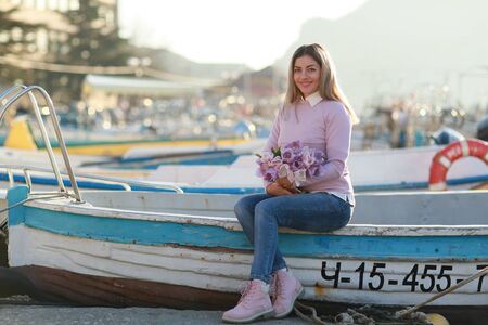 A woman Sits on a fishing boat in the Bay with fishing boats.