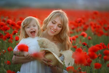 Woman beautiful blonde mom with baby in arms in poppy field.の写真素材