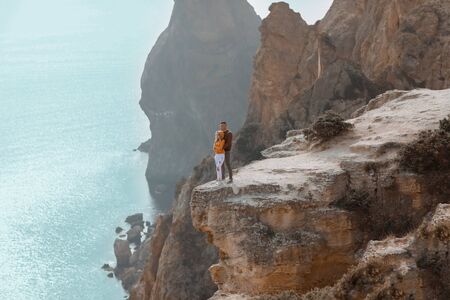 A young couple of sweethearts cuddle on top of a stone mountain with a backdrop of rocks.の写真素材