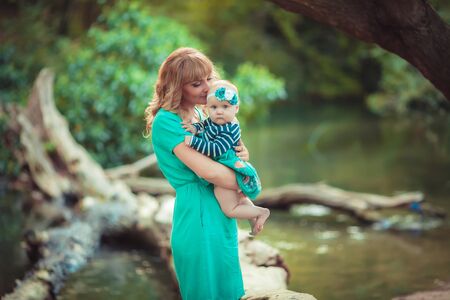 A family of two people mother and daughter baby sit in nature near lakes and between trees.の写真素材