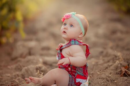 Close up of a small child girl sitting on the ground.