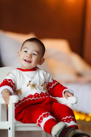Cheerful boy 2-3 years of Asian appearance in a room at home in a red Christmas suit.の写真素材