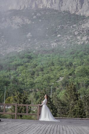 Young bride in white long dress outdoors on forest background.の写真素材