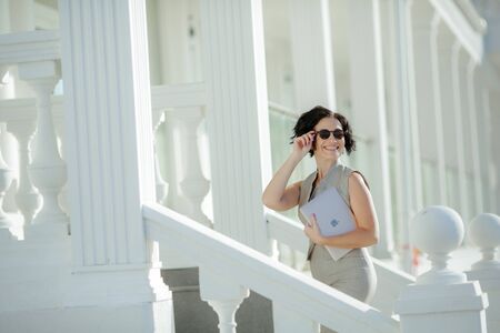 An adult woman climbs the white pillared steps to the business center.