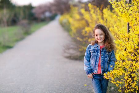 Child girl outdoor walking along the path in the Park near the trees with yellow leaves.