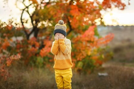 Cheerful child boy in warm clothes stands in front of the camera and grimaces.の写真素材