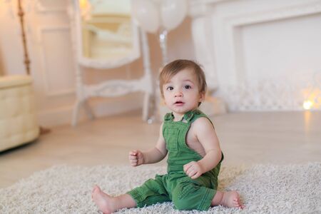 Boy 1 year sitting on the carpet in a bright room.の写真素材