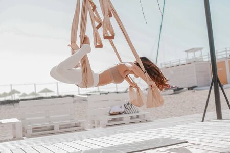 Woman on the beach in sportswear doing sports on hanging hammocks.の写真素材