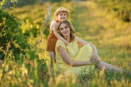 Mother is a grown woman hugging a child in a boundless green field.の写真素材