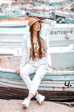 A young girl in a white suit sits on the stern of a pleasure boat.の写真素材