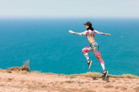 Female athlete on the sea coast performs exercises before training and running