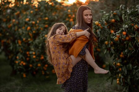 Mom and daughter have fun together and play in the garden with Agriculture trees.の写真素材