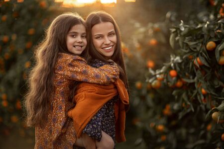 Mom and daughter have fun together and play in the garden with Agriculture trees.の写真素材