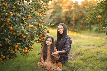 Mom and daughter have fun together and play in the garden with Agriculture trees.