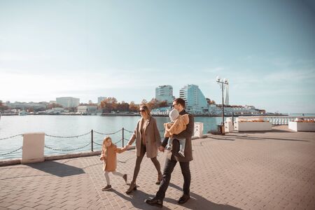 A young happy family of four walks in the spring on a sunny day. Husband and wife with two childrenの写真素材
