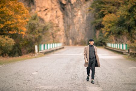One male model dressed with a stylish coat and a fall cap outside.の写真素材